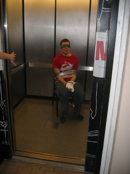 Steve duct-taped to a chair in an elevator